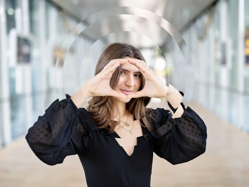 Woman smiling, forming the Onehealth logo with her hands in front of her face in a modern setting.