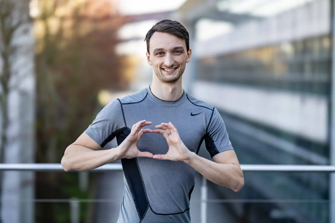 Homem sorridente segurando uma grande bola esportiva.