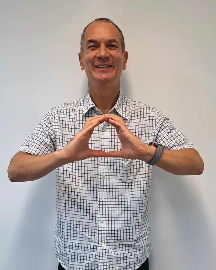 Homem sorridente formando o logotipo da OneHealth com as mãos.