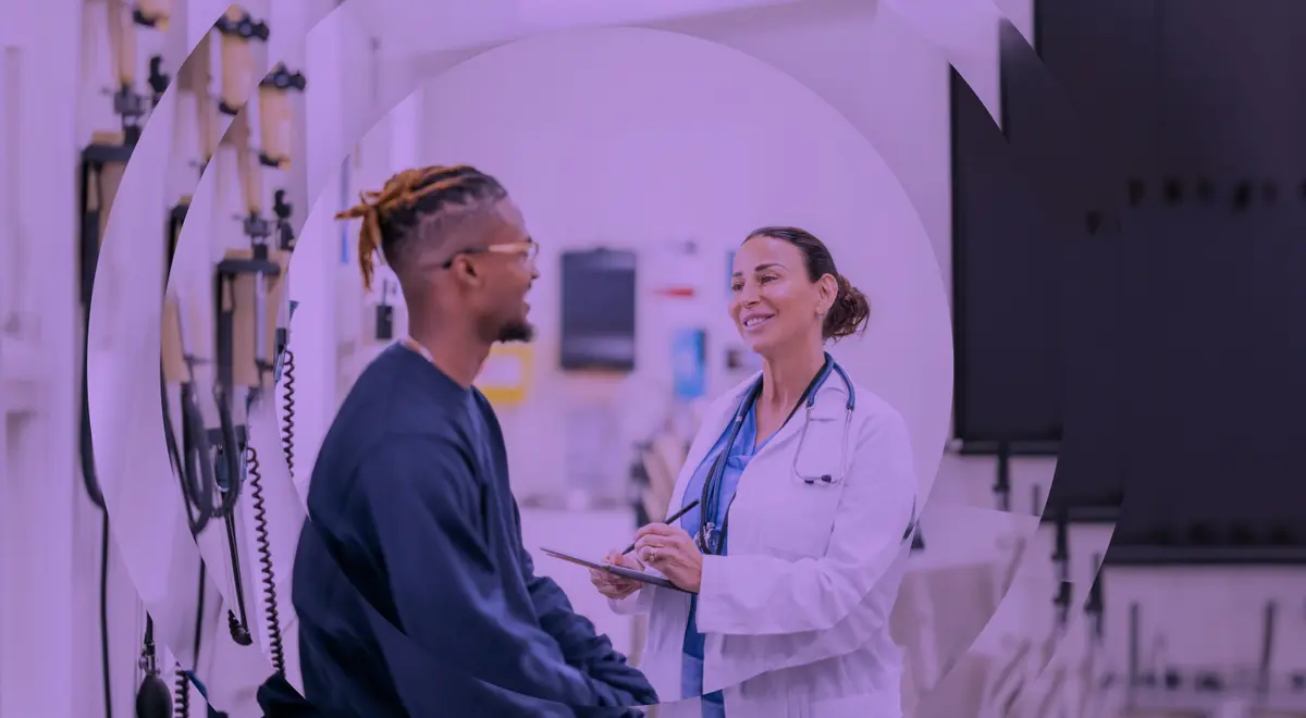 Un bărbat zâmbitor care poartă ochelari vorbește cu un medic care ia notițe, într-un context medical.