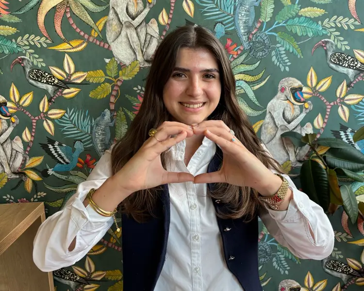 Gülümseyen kadın, modern bir çerçeve içinde elleriyle yüzünün önünde bir çerçeve oluşturuyor.